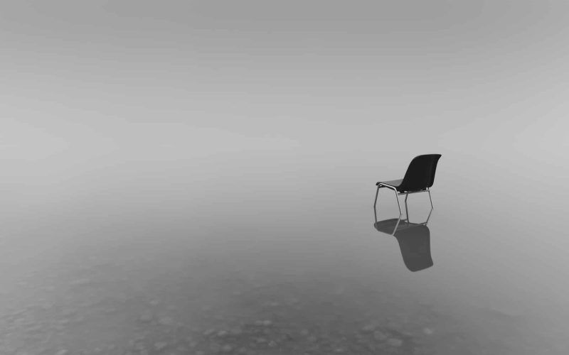 A greyscale shot of a chair on a water surface with a reflection on a rainy day